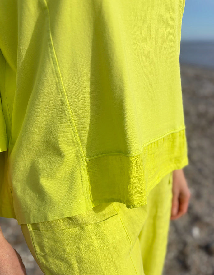 Person wearing a bright yellow outfit on a beach.