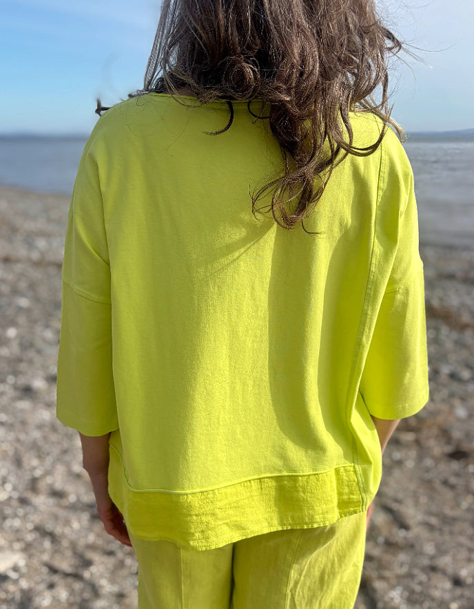 Person wearing a bright yellow outfit standing on a beach.
