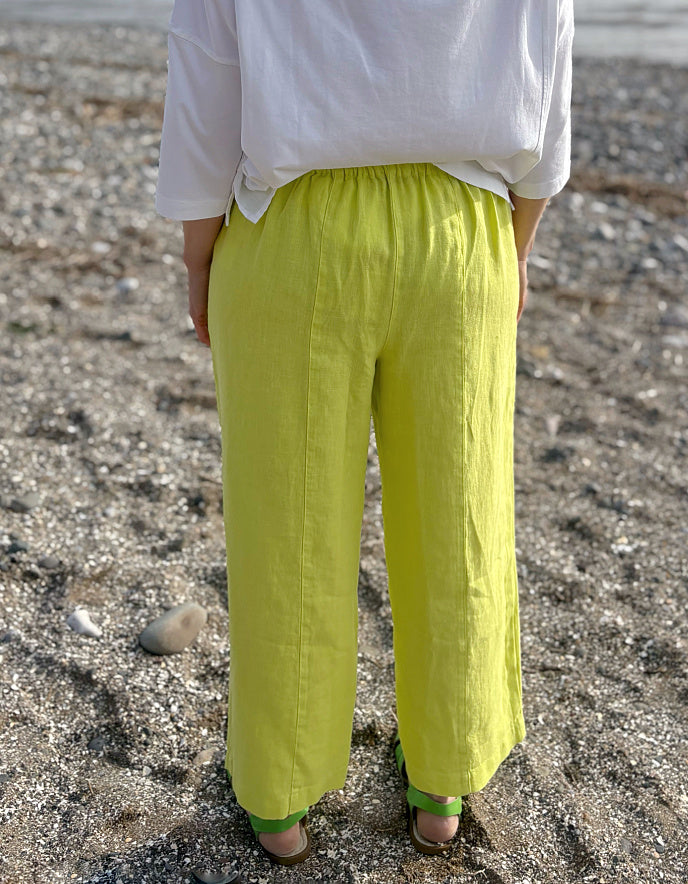 Person wearing bright green pants and a white top on a rocky surface
