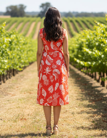 Woman in a red dress with white patterns standing in a vineyard