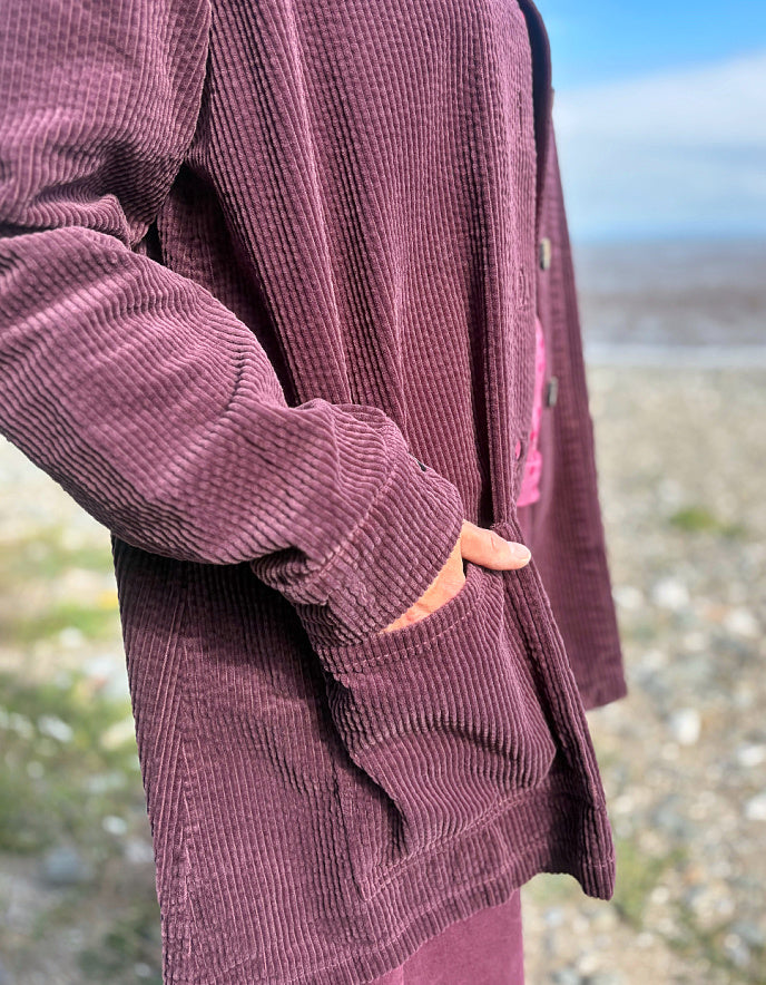 Close-up of a person wearing a corduroy jacket with a blurred natural background