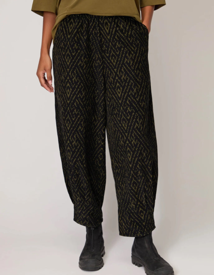 Person wearing black patterned pants on a white background