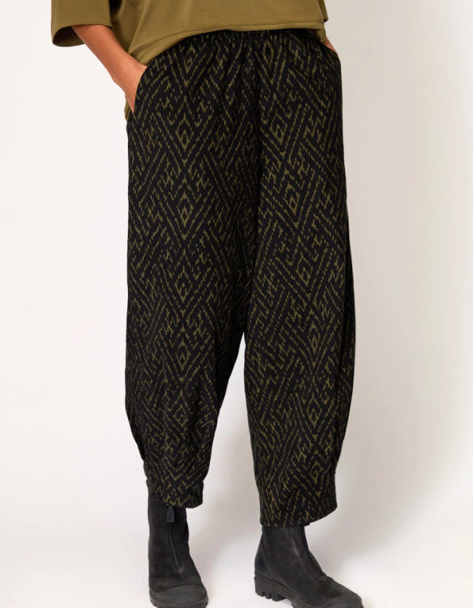 Person wearing black patterned pants on a white background