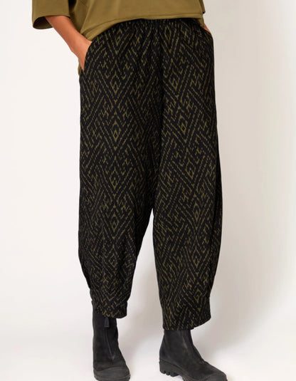 Person wearing black patterned pants on a white background
