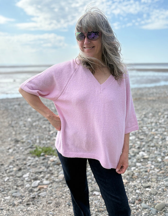 Woman wearing a pink sweater on a beach