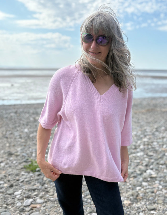 Woman wearing a pink sweater on a beach