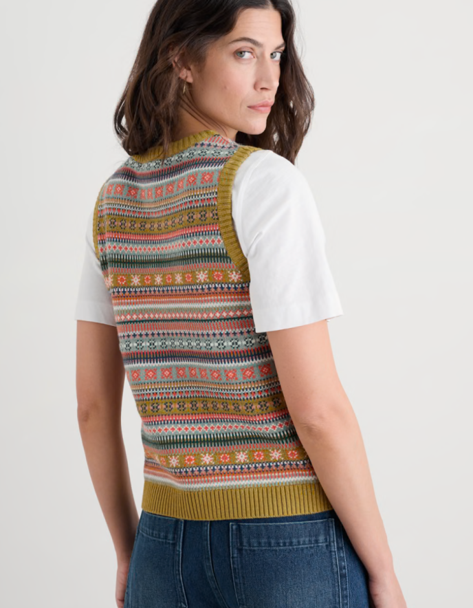 Woman wearing a colourful fair Isle Tank top over a white shirt on a plain background