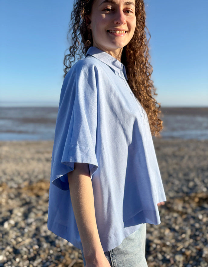 Person wearing a light blue shirt on a beach