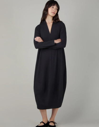 Woman wearing a black v neck bubble dress against a neutral background