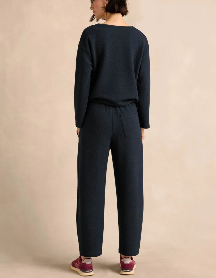 Close-up of a person wearing dark navy textured knit trouser