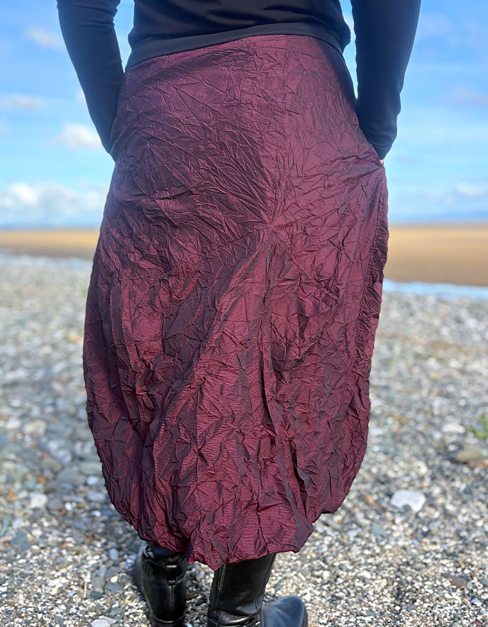 Person wearing a burgundy textured skirt on a beach