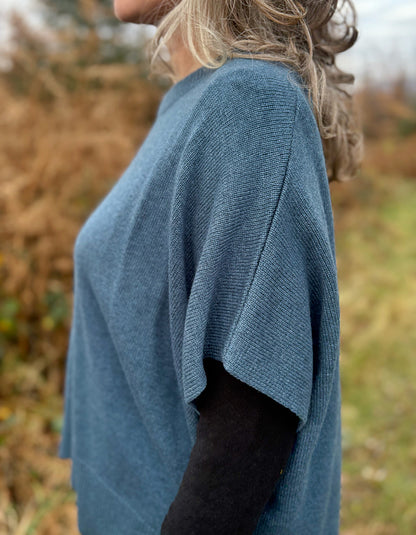 Person wearing a blue sweater in a natural setting