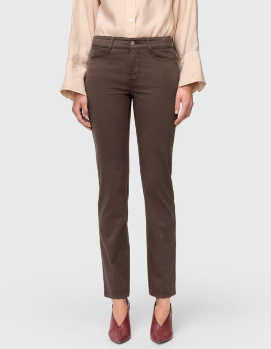 A model from the waist down wearing dark brown straight-leg jeans, a light beige blouse, and burgundy pointed-toe heels, set against a plain light gray studio background.