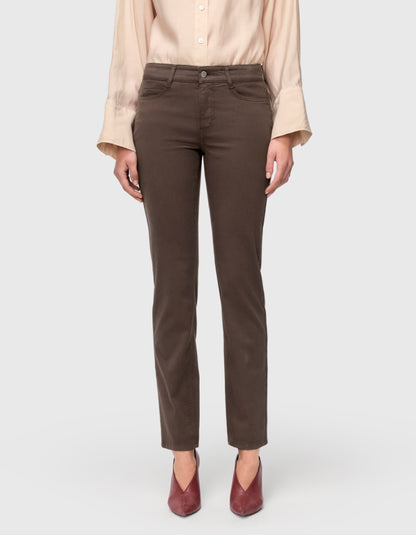 A model wearing a pair of straight-leg brown pants, paired with a light beige blouse and burgundy pointed-toe heels, shown from the waist down on a light gray background.