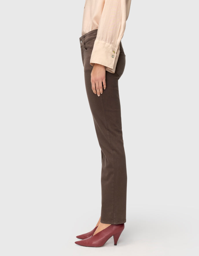 Side view of a model wearing dark brown straight-leg corduroy pants, a light beige long-sleeve blouse, and burgundy pointed-toe kitten heel pumps, set against a solid light gray background.