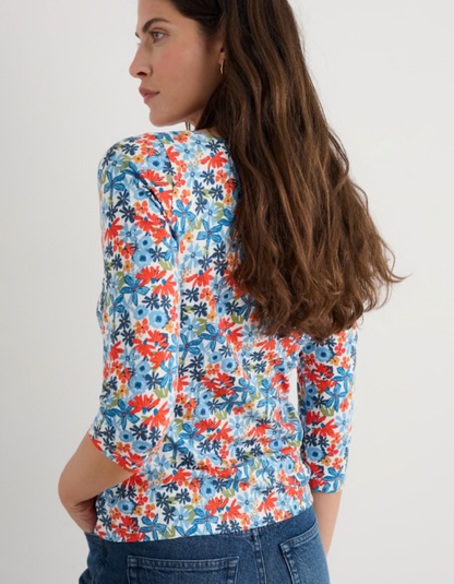 Woman wearing a colourful floral cotton jersey t shirt top with a plain background