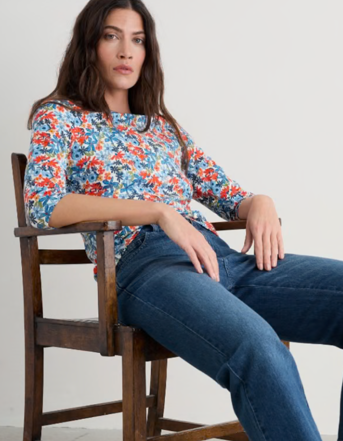 Woman wearing a colourful floral cotton jersey t shirt top with a plain background