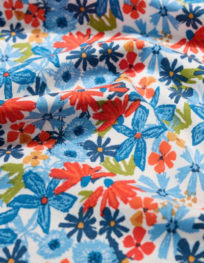 Close-up of colorful floral fabric with blue, red, and green flowers on a white background.
