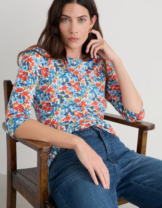 Woman wearing a colourful floral cotton jersey t shirt top with a plain background