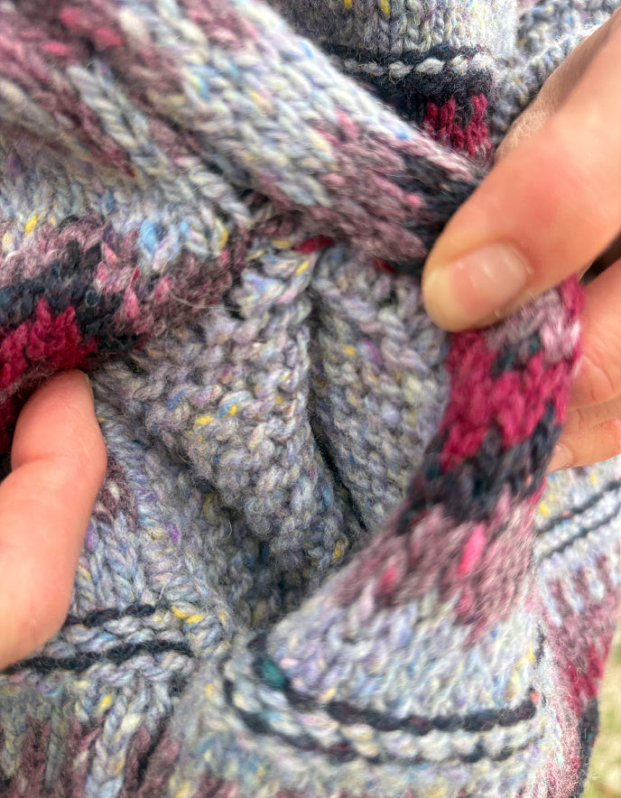Close-up of a textured fabric with multicolor pattern held by hands