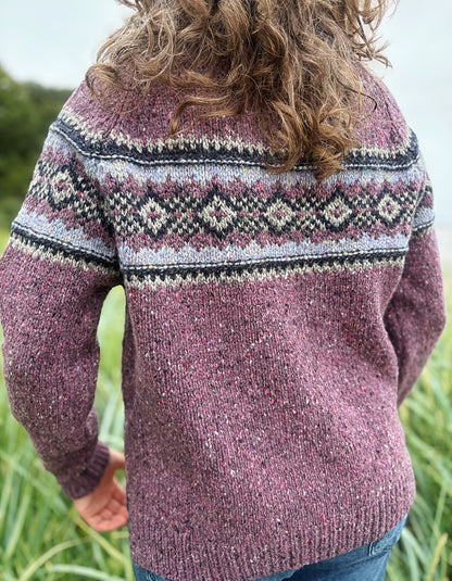 Person wearing a patterned berry Fair Isle sweater and sunglasses in a field
