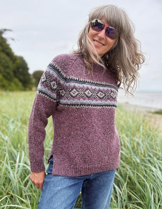 Person wearing a patterned berry Fair Isle sweater and sunglasses in a field