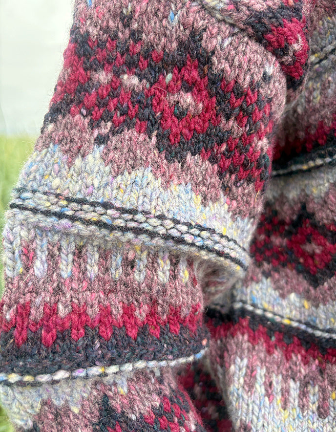Close-up of patterned knitted fabric with red, black, and gray colors.