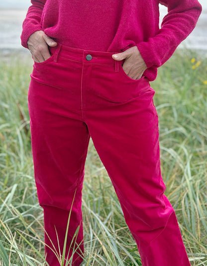 Person wearing bright pink velvet pants and a matching top standing in grass.
