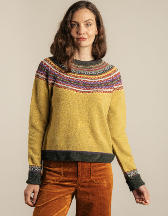 Person wearing a yellow sweater with a colourful fair Isle detail