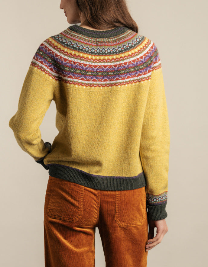 Person wearing a yellow sweater with a colourful fair Isle detail