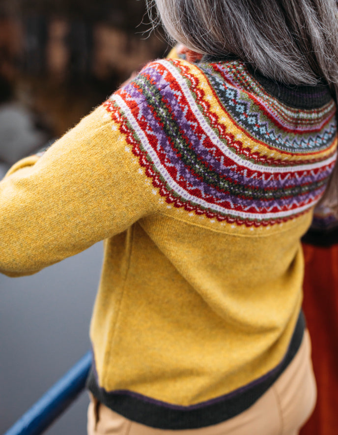 Person wearing a yellow sweater with a colourful fair Isle detail