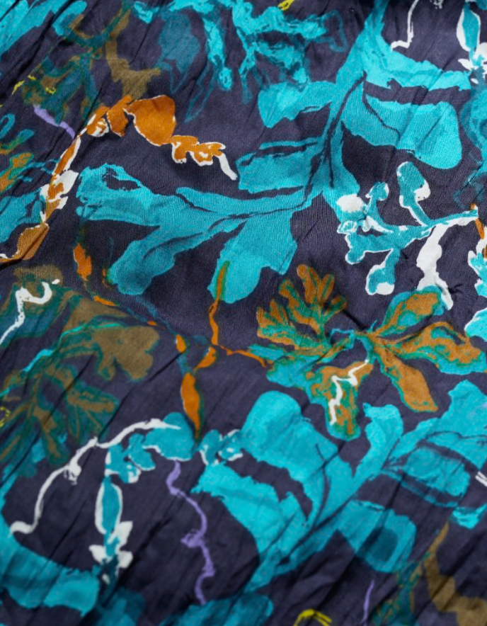 Close-up of a floral patterned fabric with teal, orange, and purple colors on a dark background.
