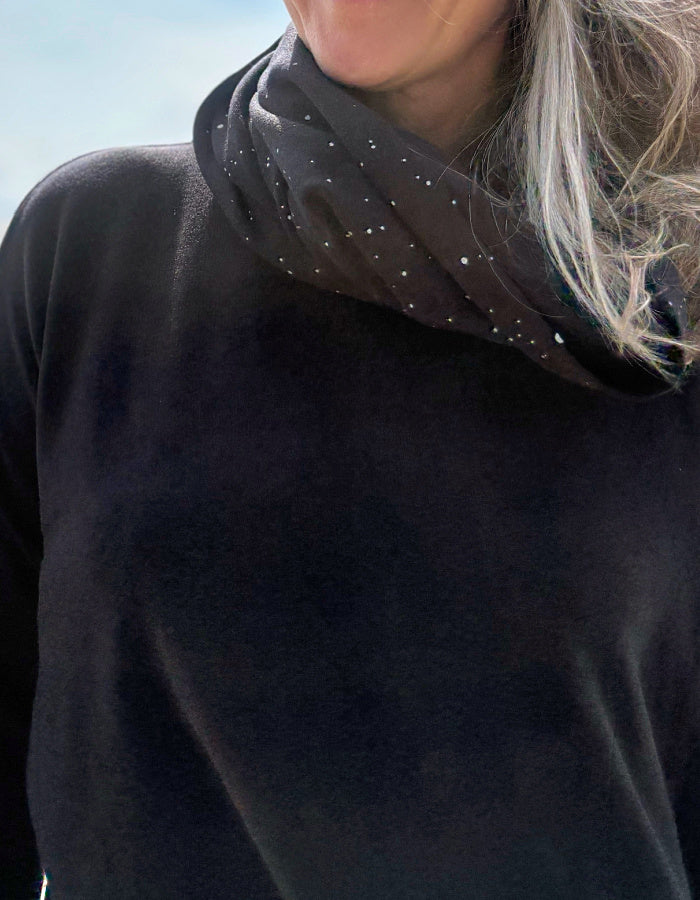 Person wearing a black snood with small white dots against a blurred background