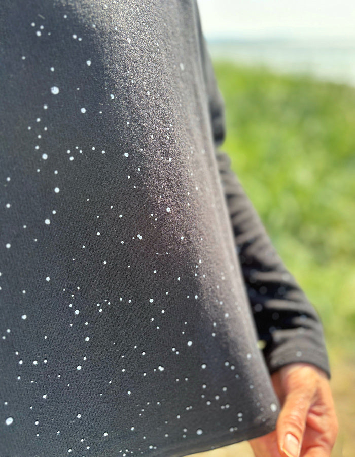 Close-up of a black fabric with white specks against a blurred natural background