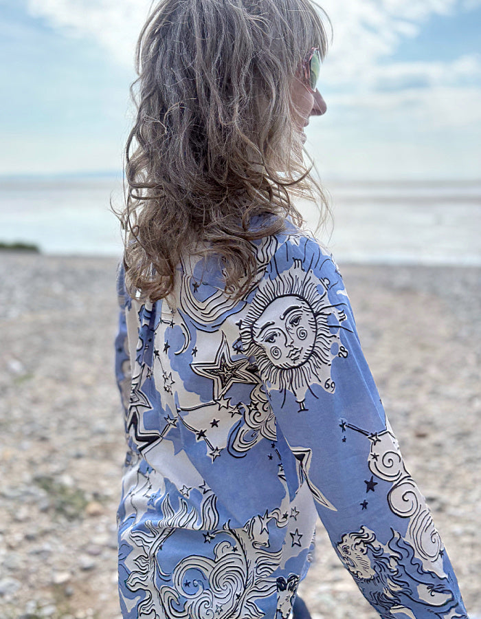 Person wearing a blue patterned shirt on a beach