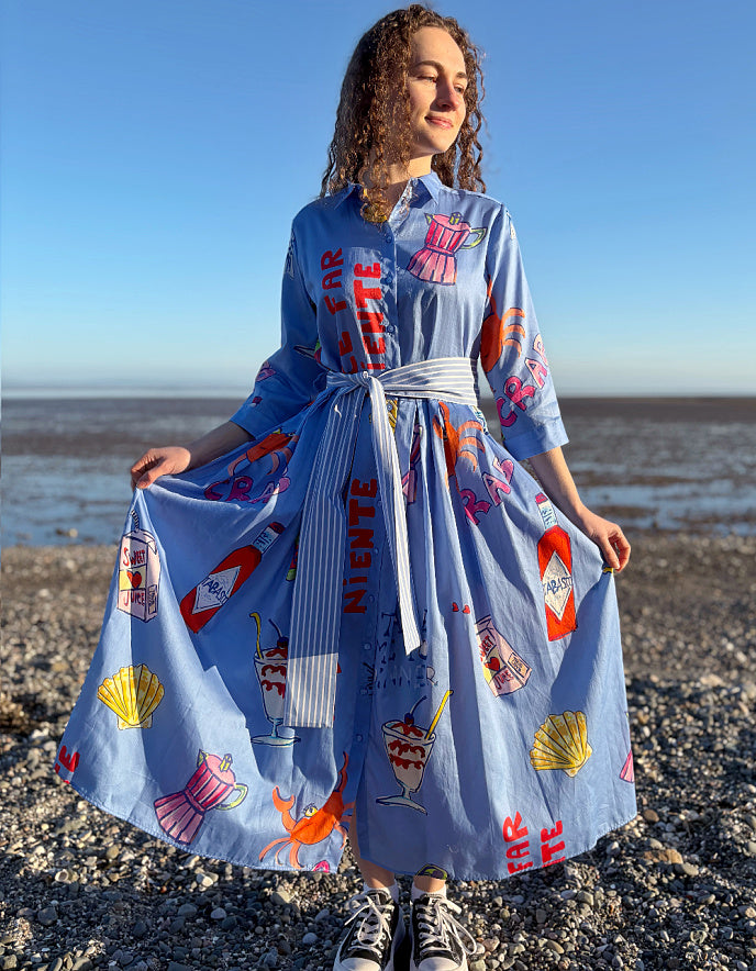 Person wearing a blue dress with colorful patterns on a beach