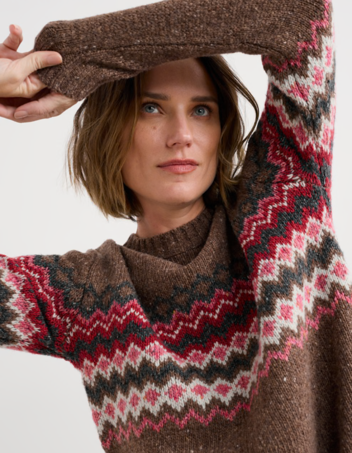 Person wearing brown and pink a fair isle patterned sweater with a neutral background