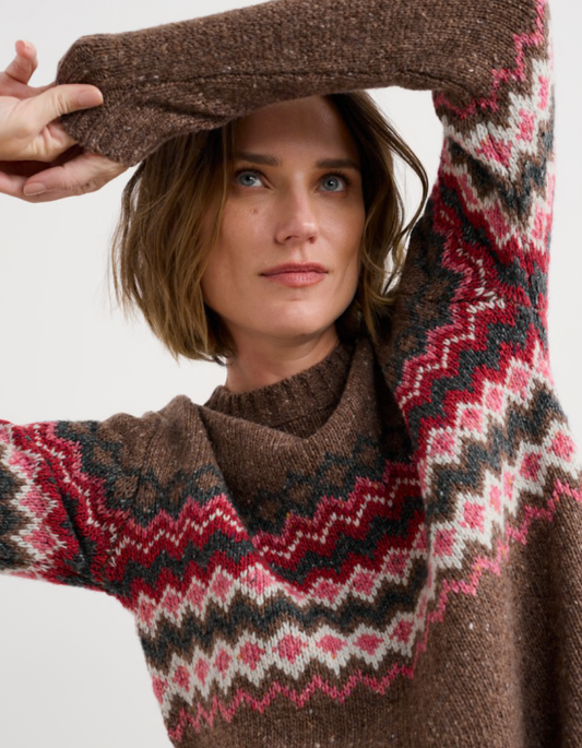 Person wearing brown and pink a fair isle patterned sweater with a neutral background