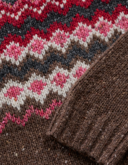 Close-up of a knitted fabric with a pattern featuring pink, red, and brown colors.