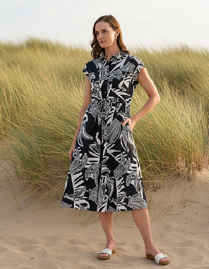 Woman wearing a black and white patterned dress standing in sand dunes