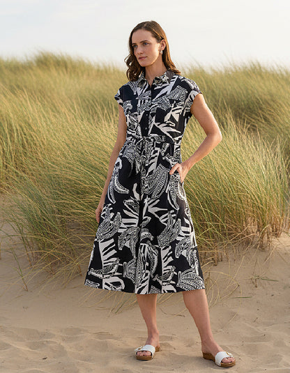 Woman wearing a black and white patterned dress standing in sand dunes