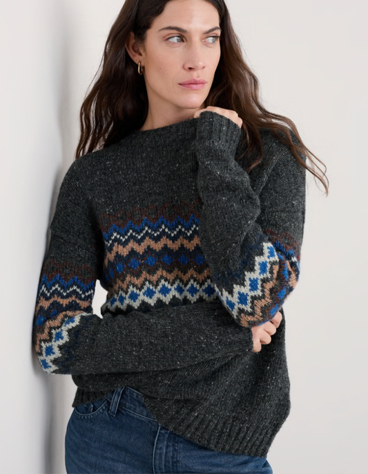 Woman wearing a dark grey tweed sweater with fair isle patterned against a white background