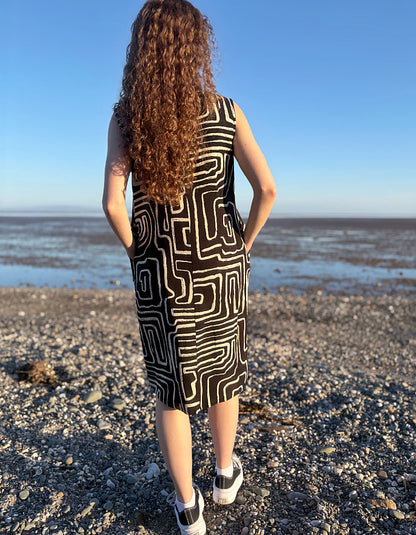 Person wearing a black and white patterned dress standing on a beach.