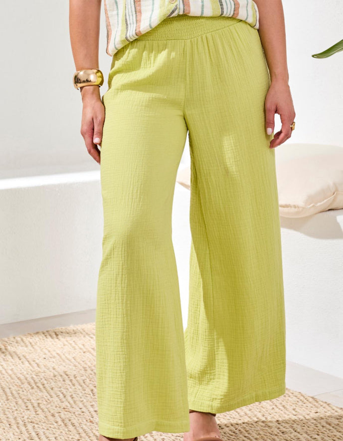 Person wearing light green wide-leg pants with a white background