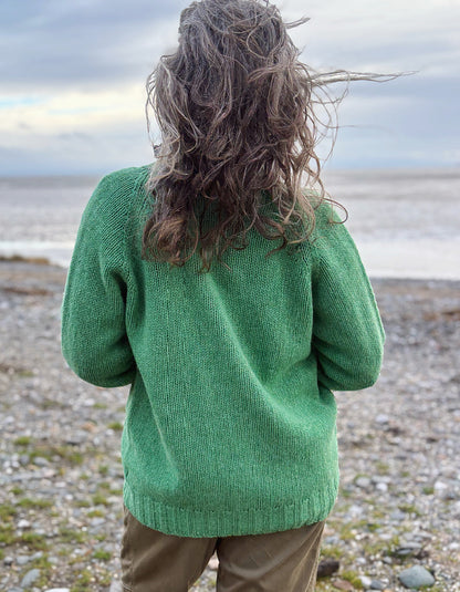 woman wearing green v neck wool cardigan on a beach