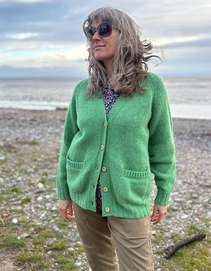 woman wearing green v neck wool cardigan on a beach