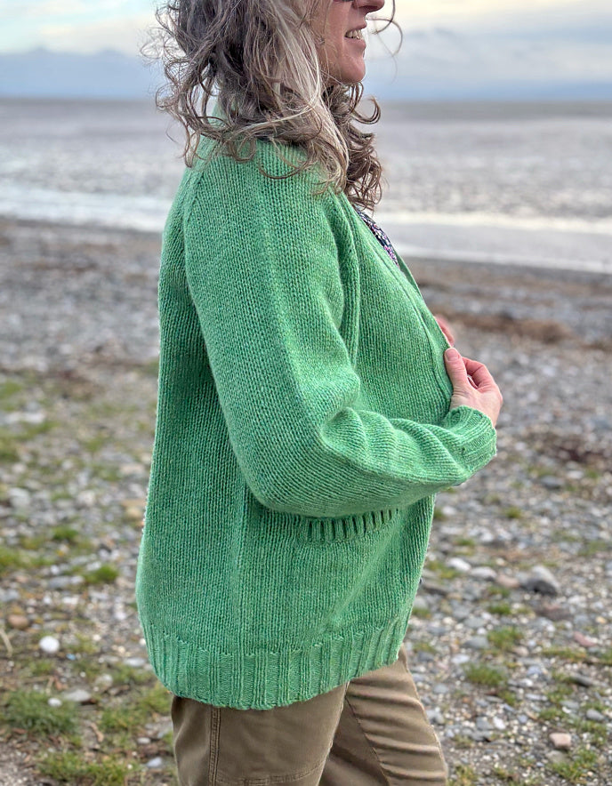 woman wearing green v neck wool cardigan on a beach
