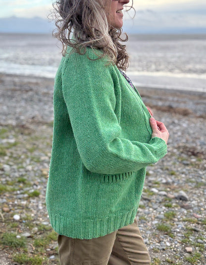 woman wearing green v neck wool cardigan on a beach