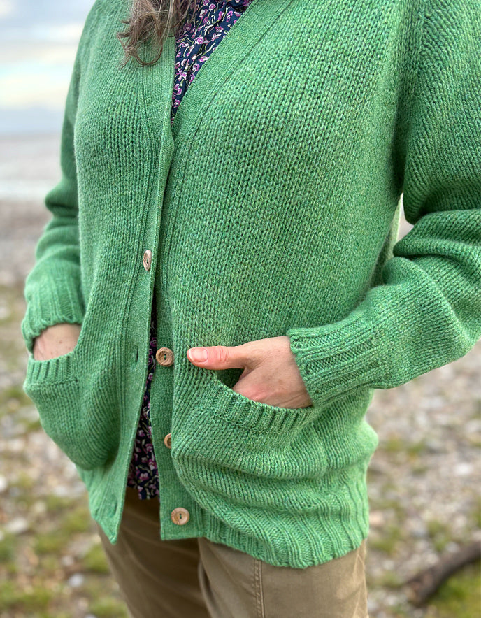 woman wearing green v neck wool cardigan on a beach