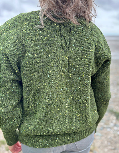 Person wearing a green knitted sweater on a beach